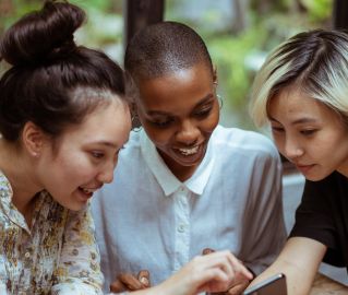 Cheerful multiethnic women browsing smartphone