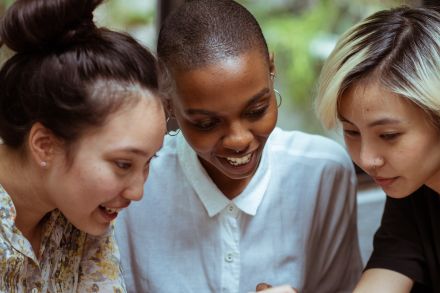 Cheerful multiethnic women browsing smartphone